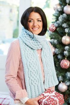 a woman standing next to a christmas tree holding a present