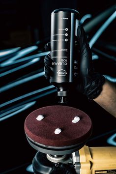 a person holding up a camera with two white dots on it's lens cap