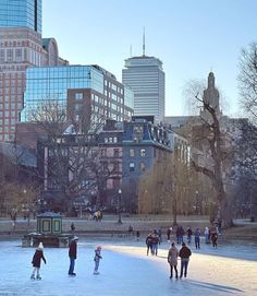 people skating on an ice rink in the middle of a city park with tall buildings