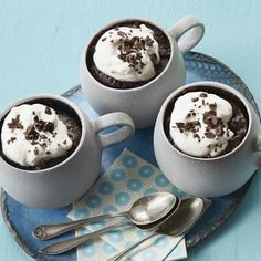 two mugs filled with dessert sitting on top of a blue plate