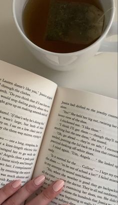 a person is reading a book and drinking tea