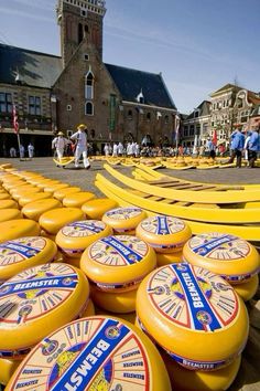 many large yellow cheeses are stacked on top of each other in front of a building