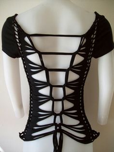 a white mannequin wearing a black top with cutouts on it's back