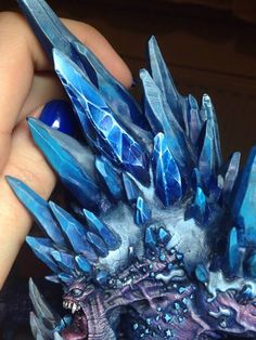 a hand holding a blue crystal dragon figurine