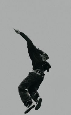 a man flying through the air while riding a skateboard in front of a gray sky