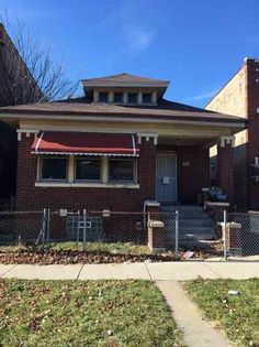 a small brick house with a red awning on the front and side of it