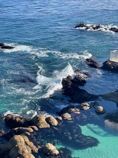 the water is crystal clear and blue with waves coming in from the rocks on the shore