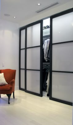 an orange chair sitting in front of a closet with sliding doors on both sides and white walls