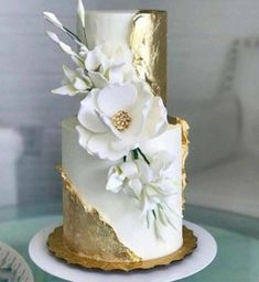 a white and gold wedding cake with flowers on top