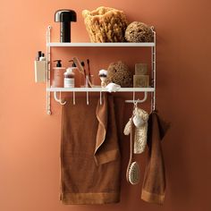 a towel rack with towels, soaps and other items on it against a pink wall