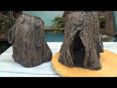 two sculptures made out of tree trunks sitting on top of a wooden table next to each other