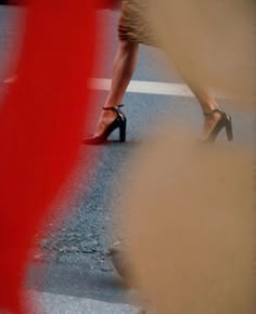 a woman in high heels walking across a street