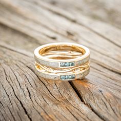 three gold rings with blue stones on top of wooden planked surface, close up