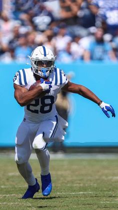 a football player running with the ball in his hand and people watching from the stands