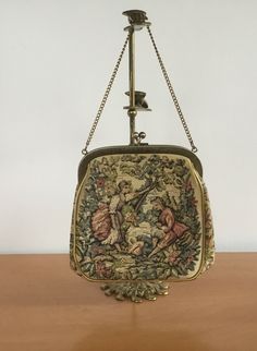 Vintage tapestry handbag Julius Resnick Miami, JR purse floral courting couple with gold tone Clasp and Chain Strap. A collectible vintage accessory from the 1950s, this elegant Julius Resnick Purse features exceptional quality materials and fine craftsmanship. Beige lining. This classic handbag will elevate your every day look. The gold chain handle adds a touch of elegance to this timeless piece. Has a snap top closure. Inside reads "J.R. Miami, USA". The writing is faded. Measures 6 1/4 inche Tapestry Handbags, Classic Handbags, Vintage Tapestry, Chain Strap, Vintage Accessories, Clutch Handbag, Gold Tone Metal, Timeless Pieces, Evening Bags