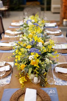 a long table with yellow and blue flowers on it is set for a formal dinner