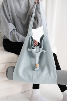 a woman sitting on a white couch holding a blue bag