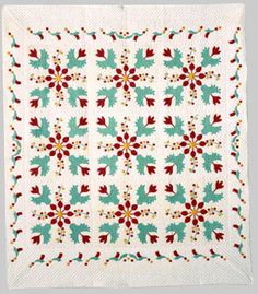 a white quilt with red and green flowers on it