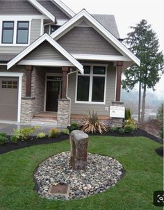 a house with landscaping in front of it and a tree stump on the lawn next to it