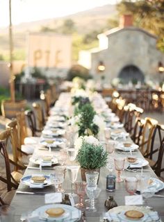 a long table is set up with plates and place settings for an outdoor dinner party