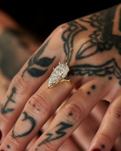 a woman's hand with tattoos and a diamond ring on her left hand,