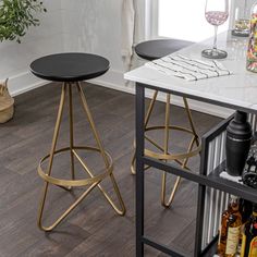 two black and gold bar stools sitting on top of a wooden floor next to a counter