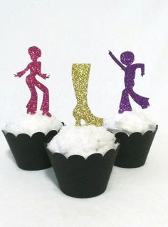 three cupcakes with glitter figures on them