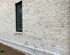 the side of a brick building with a window on one side and an empty sidewalk in front