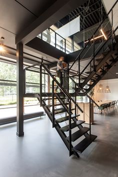 a man is walking up the stairs in a modern building with glass walls and steel railings