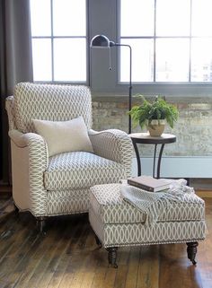 a chair and ottoman in front of a window with a potted plant on it