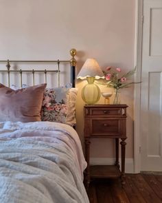 a bedroom with a bed, nightstand and flowers on the night stand next to it