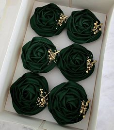 six green flowers in a white box with gold pins and pearls on each flower head