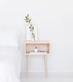 a white bed sitting next to a wooden table with a plant on top of it