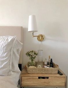 a bed with white sheets and pillows next to a night stand with bottles on it