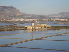 an old building is surrounded by water and mountains