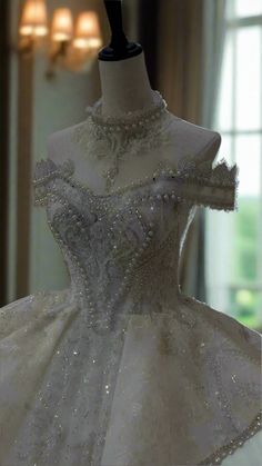 a wedding dress on display in a room with chandeliers and lights hanging from the ceiling