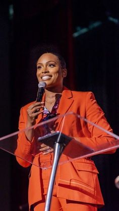 a woman in an orange suit holding a microphone