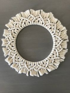 a circular white doily with fringes on a gray tableclothed surface in the shape of a circle