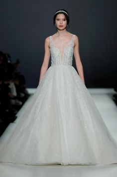 a woman in a white wedding dress on the runway