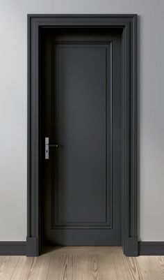 an empty room with a black door and wood flooring on one side, gray walls in the other