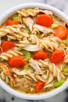 a bowl of chicken noodle soup with carrots, celery and noodles