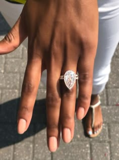 a close up of a person's hand with a diamond ring on their finger