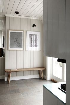 a kitchen with two pictures hanging on the wall and a bench in front of it