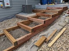 some wood is laying out on the ground in front of a house with an air conditioner