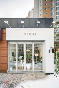 the front entrance to a store with glass doors and plants in pots on the outside