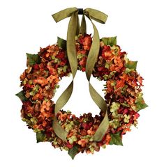 an orange and green wreath hanging on a white wall next to a brown ribbon tied around it