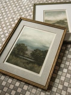 two framed pictures sitting next to each other on a tiled floor with white and gray tiles