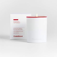 a white candle with red trim next to a box on a white surface, in front of a white background