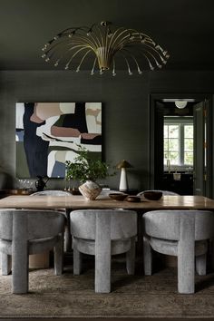 the dining room table is surrounded by two stools and a large painting on the wall