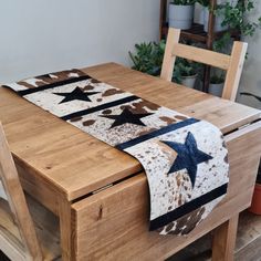 a wooden table topped with a cowhide and star quilted placemat on top of it